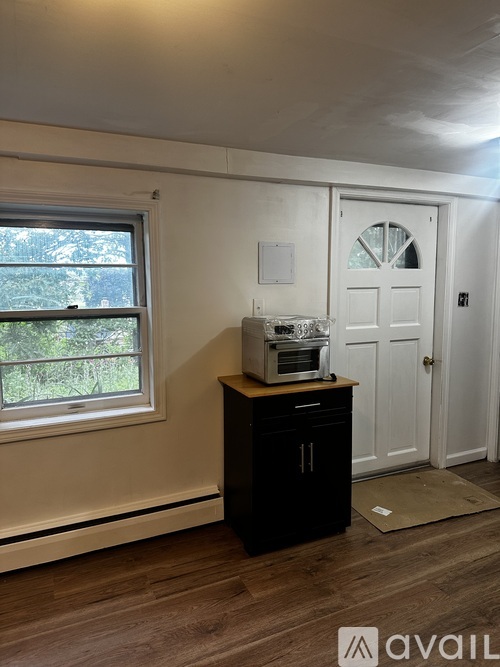 A room with a window, a microwave, and a door.