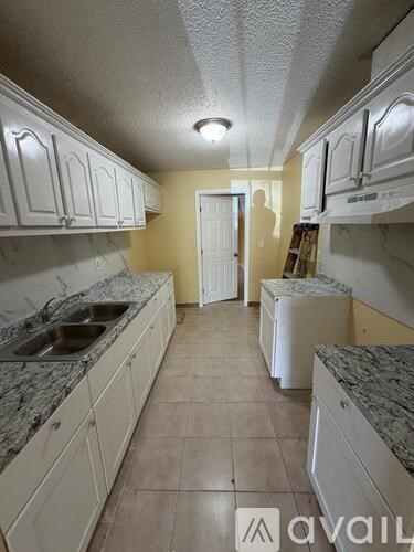 A kitchen with white cabinets and a marble countertop.