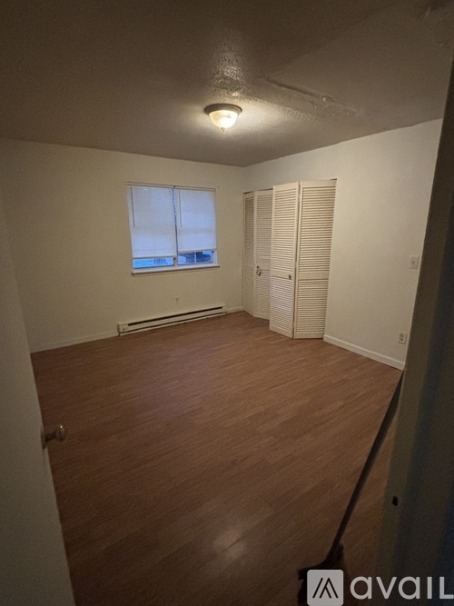 A room with wooden flooring and white walls.