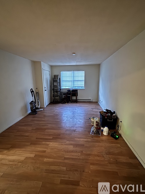 A room with wooden flooring and a window with blinds.