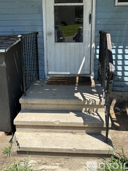 A person is standing in the doorway of a blue house.