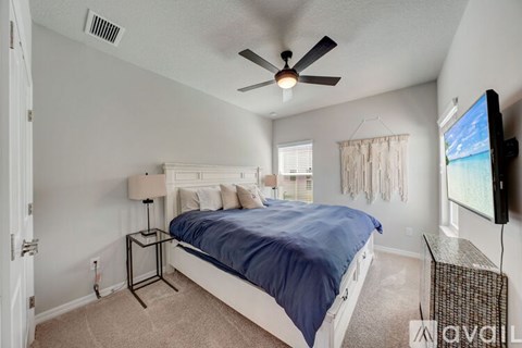 A bedroom with a bed, a ceiling fan, and a television.