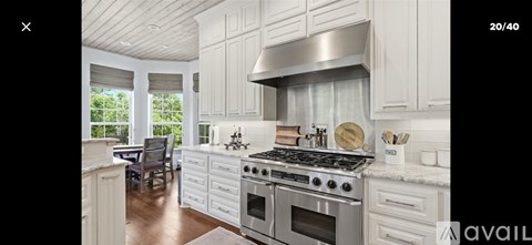A modern kitchen with white cabinets and a stainless steel range hood.
