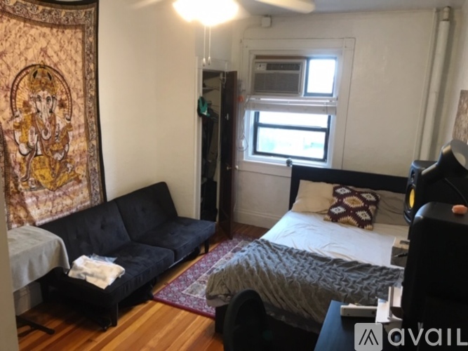 A bedroom with a bed, couch, and a tapestry hanging on the wall.