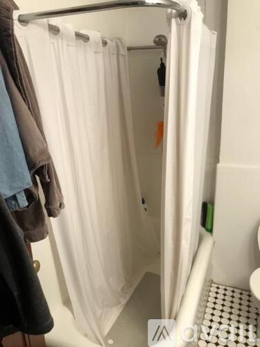 A white shower curtain is hanging in a bathroom.