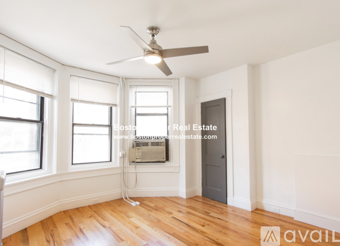 A room with a ceiling fan and wooden flooring.