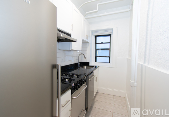 A small kitchen with white appliances and a window.