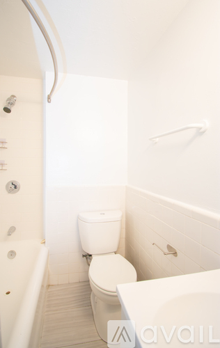 A white toilet in a small bathroom with a bathtub.