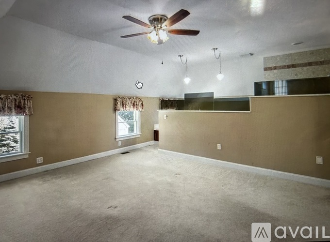 A spacious room with a ceiling fan and a window with curtains.