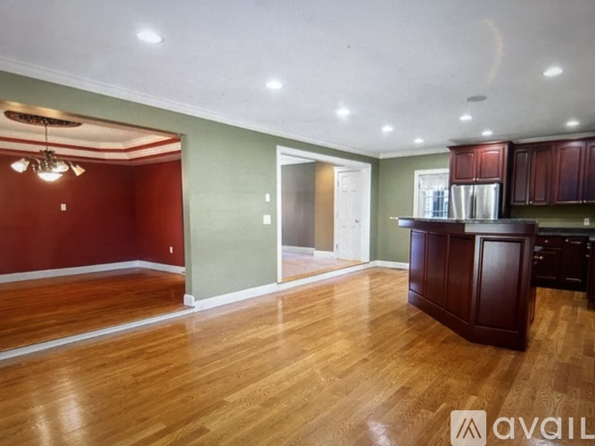 A room with wooden floors and a kitchen area with brown cabinets.