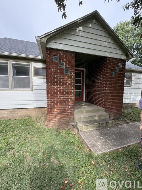 A small house with a brick pillar and a glass door.