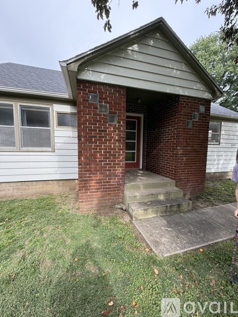 A small house with a brick pillar and a glass door.