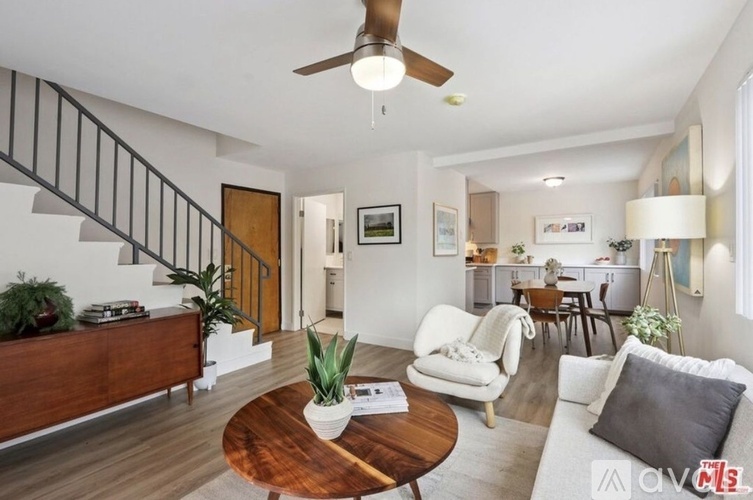 A living room with a staircase and a ceiling fan.