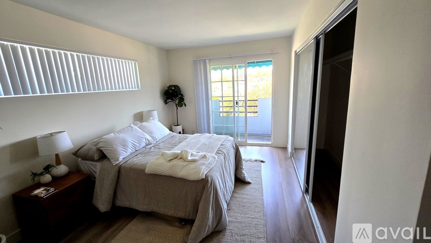 A bedroom with a large bed and a window with blinds.