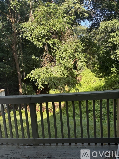 A balcony with a railing and a view of a green lawn and trees.
