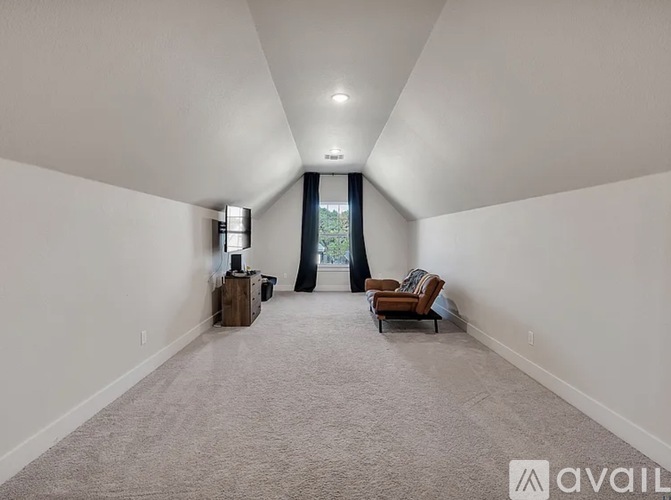 A spacious room with a carpeted floor and a window with curtains.
