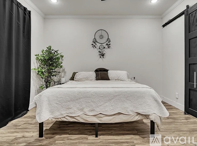 A bedroom with a large bed and a plant on the side.