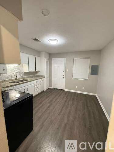 A kitchen with a black dishwasher and white cabinets.