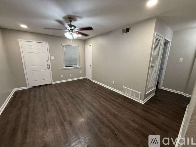 A room with a ceiling fan and wooden flooring.