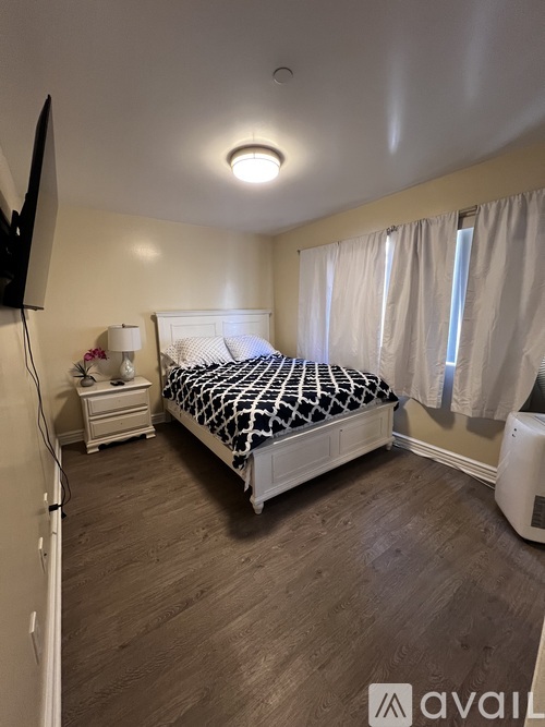 A bedroom with a bed, nightstand, and television.