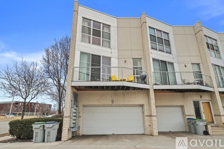 A two-story residential building with a balcony and garage doors.