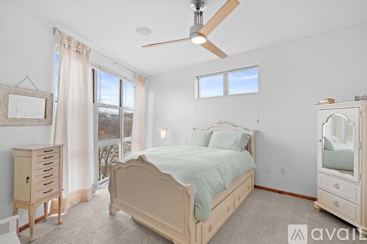 A bedroom with a large bed, a dresser, and a ceiling fan.