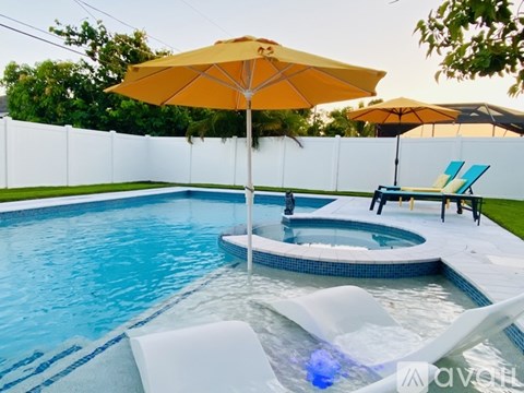A pool with a yellow umbrella and two chairs.