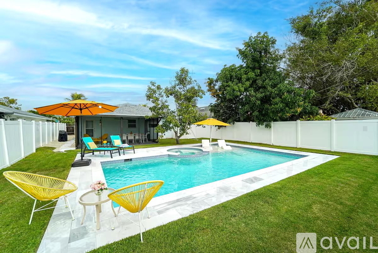 A pool area with a white fence and a house in the background.