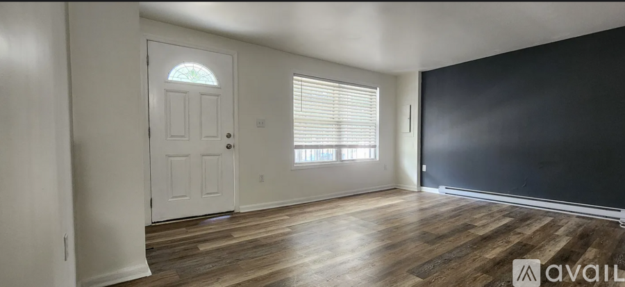 A room with a white door and wooden flooring is available for rent.