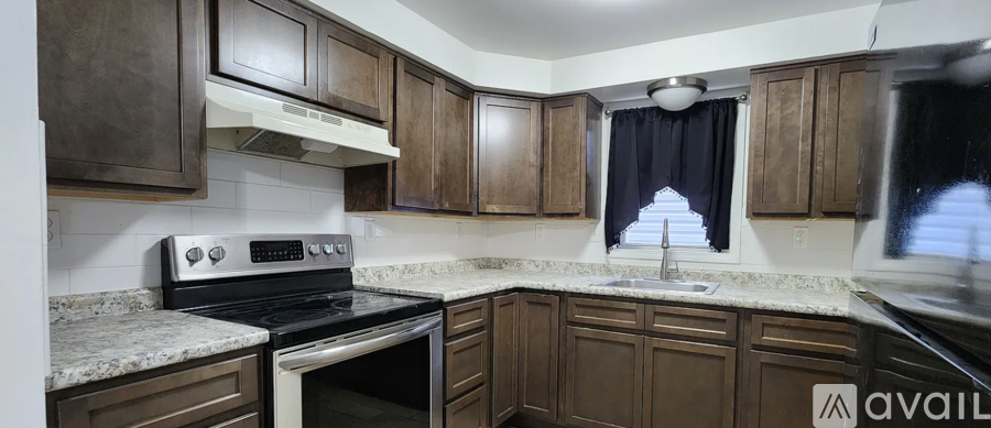 A kitchen with dark wood cabinets and a granite countertop.