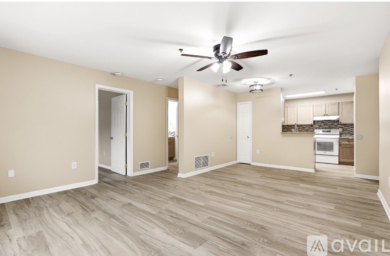 A spacious room with a ceiling fan and hardwood flooring.
