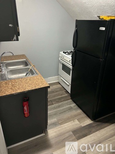 A black refrigerator sits next to a stove in a kitchen.