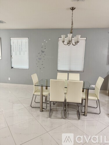 A dining room with a glass table and white chairs.