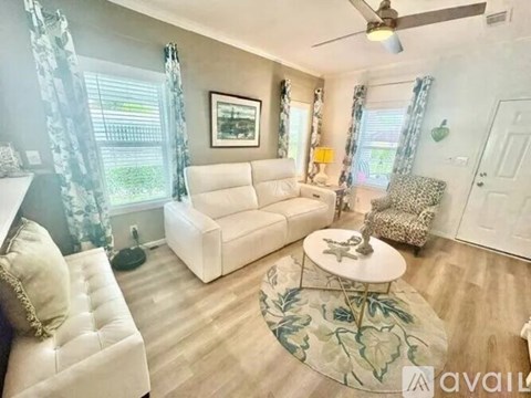 A living room with a white couch, a small table, and a rug with a leaf pattern.