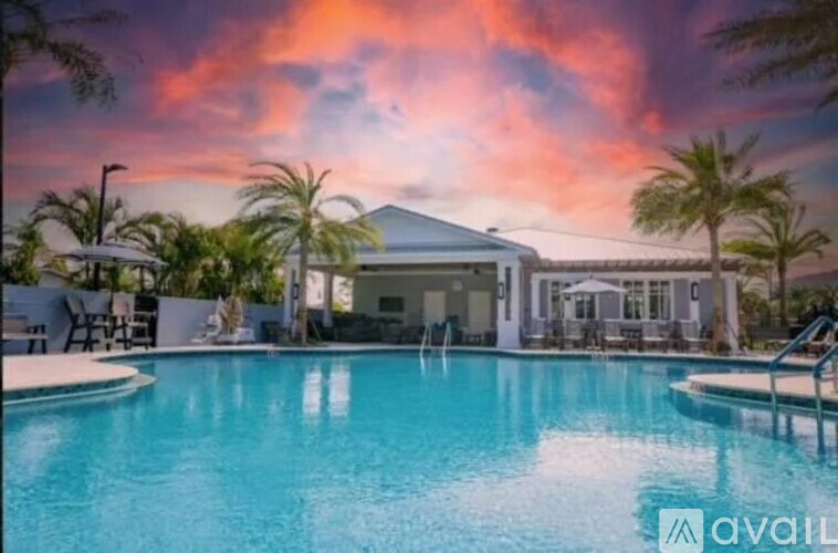 A pool in front of a house with a sunset in the background.