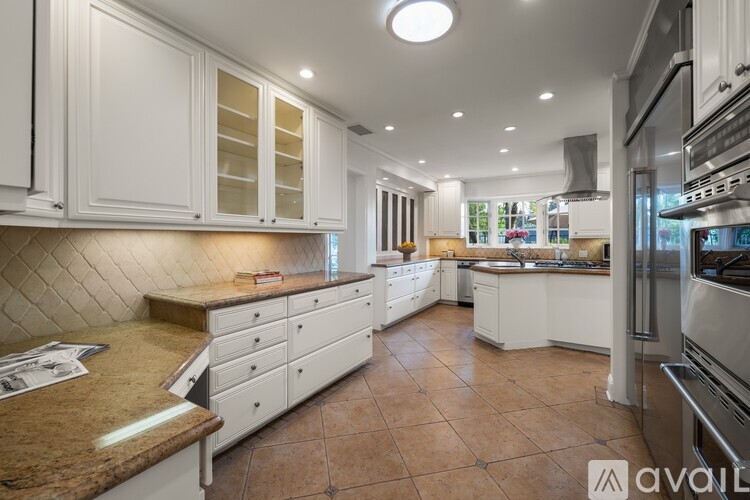 A kitchen with white cabinets and brown countertops is available for rent.