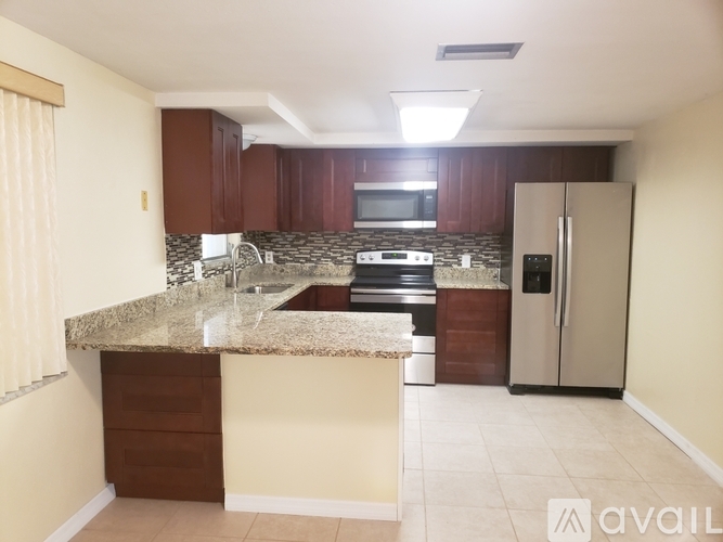A kitchen with brown cabinets and a granite countertop.