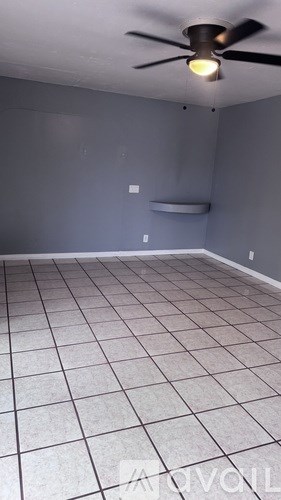 A room with a ceiling fan and tile flooring.
