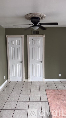 A room with two white doors and a ceiling fan.