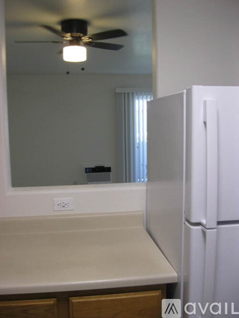 A white refrigerator in a kitchen with a ceiling fan.