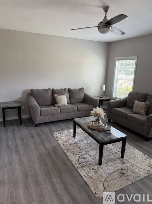A living room with a grey couch, a coffee table, and a ceiling fan.
