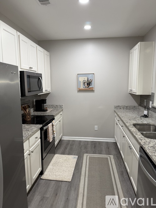 A kitchen with white cabinets and a grey floor.