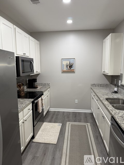 A kitchen with white cabinets and a grey floor.
