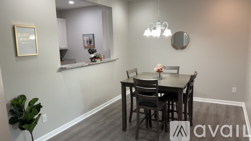 A dining room with a table set for two and a plant on the side.