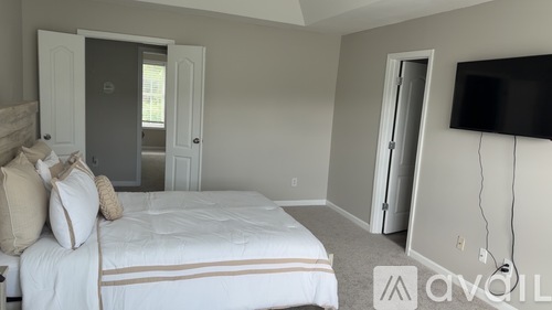A bedroom with a bed, a television, and a window.