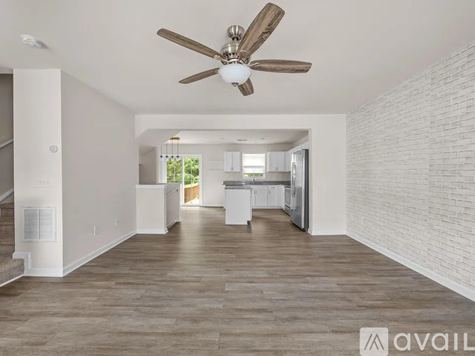 A spacious living room with a ceiling fan and hardwood flooring.