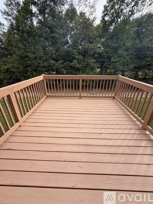 A wooden deck with a railing and trees in the background.