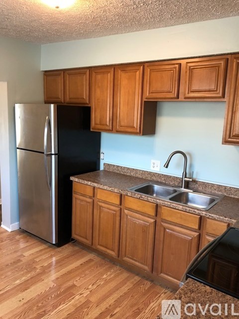 A kitchen with wooden cabinets and a black refrigerator.