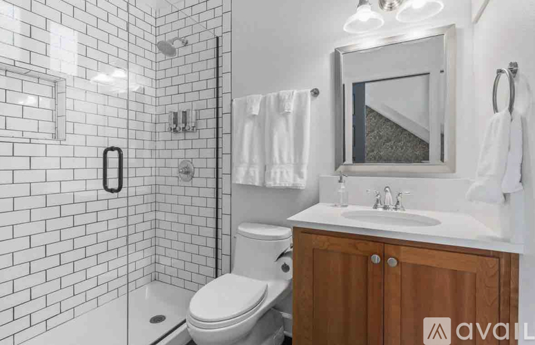 A white tiled bathroom with a toilet, sink, and mirror.