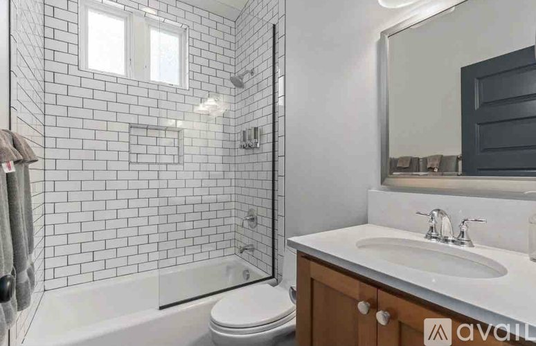 A white tiled bathroom with a toilet, sink, and bathtub.